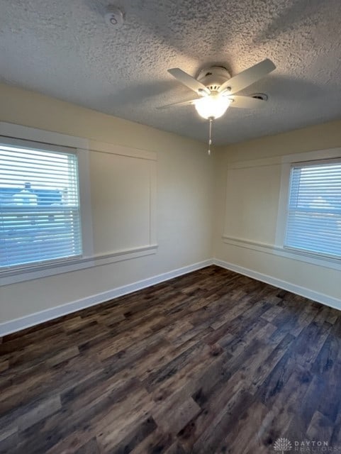 empty room featuring ceiling fan, dark hardwood / wood-style flooring, plenty of natural light, and a textured ceiling