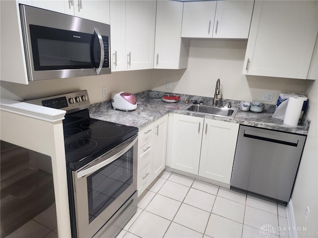 kitchen featuring light tile patterned flooring, sink, white cabinetry, light stone countertops, and stainless steel appliances