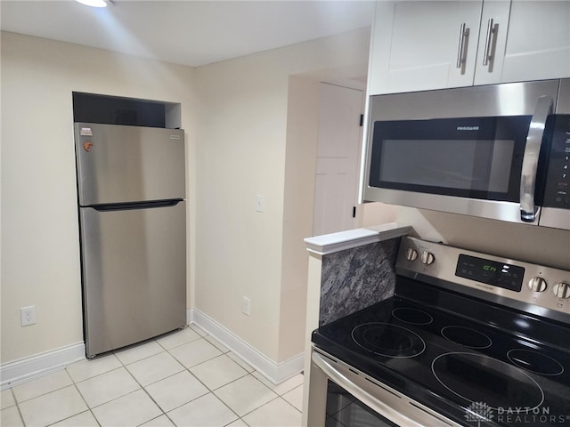 kitchen with light tile patterned flooring, stainless steel appliances, and white cabinetry