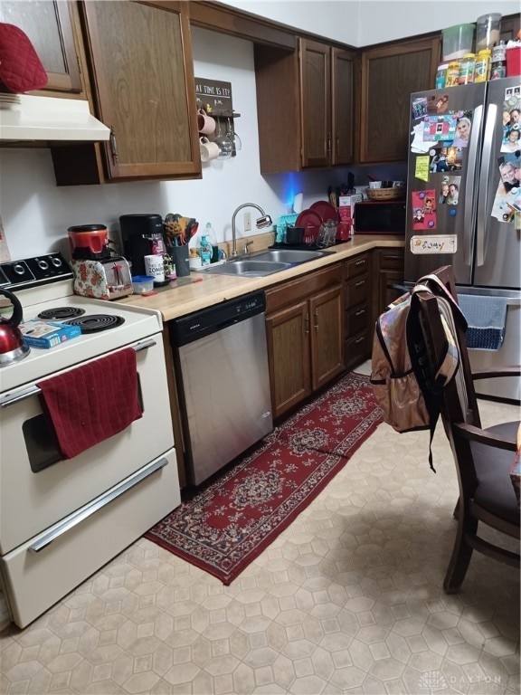 kitchen with appliances with stainless steel finishes, dark brown cabinets, and sink