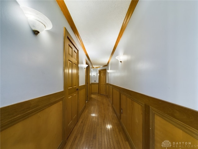 corridor featuring hardwood / wood-style floors, a textured ceiling, and ornamental molding