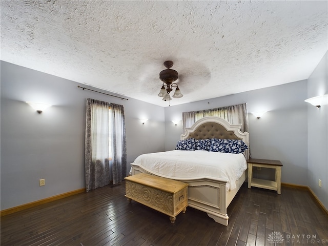 bedroom with dark wood-type flooring, a textured ceiling, and ceiling fan