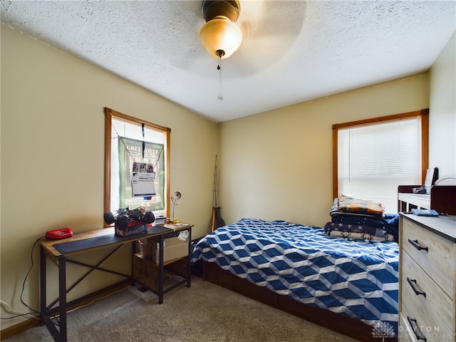 bedroom featuring a textured ceiling, dark carpet, and ceiling fan