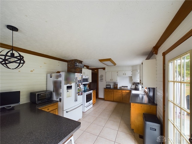 kitchen with decorative light fixtures, white appliances, sink, wood walls, and a textured ceiling