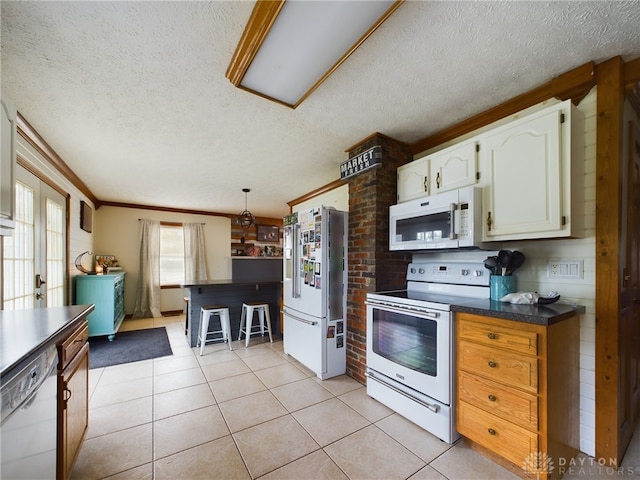 kitchen with crown molding, light tile patterned floors, white appliances, and white cabinets