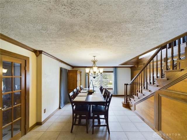 tiled dining room with ornamental molding, a notable chandelier, and a textured ceiling