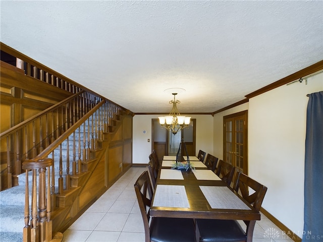 tiled dining space with ornamental molding, a notable chandelier, and a textured ceiling