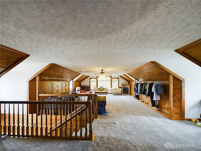 additional living space with a textured ceiling, carpet flooring, vaulted ceiling, and ceiling fan