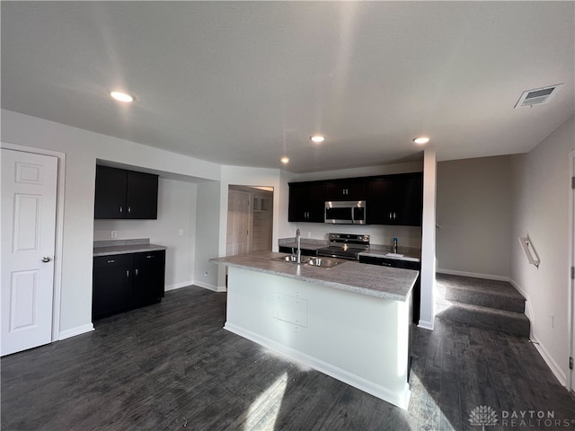 kitchen with dark hardwood / wood-style floors, stainless steel appliances, sink, and a kitchen island with sink