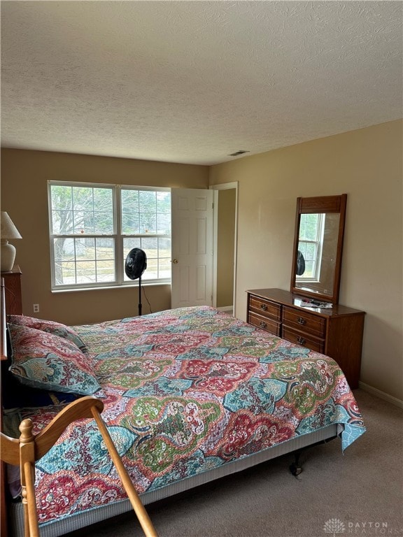 bedroom featuring multiple windows, a textured ceiling, and carpet flooring