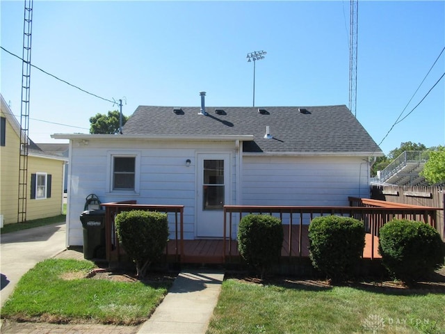 rear view of house featuring a lawn and a deck