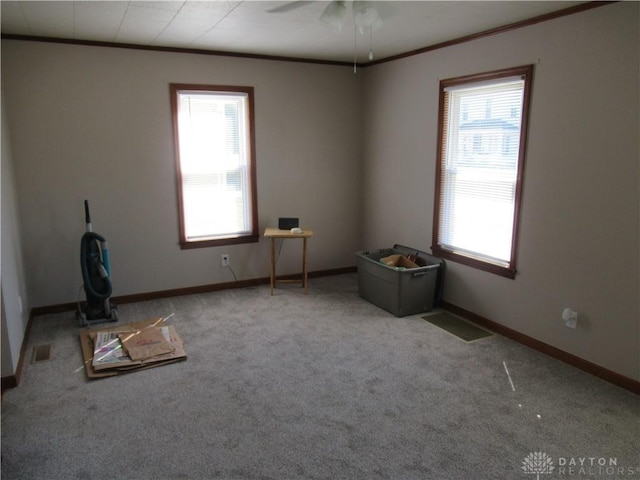 spare room with plenty of natural light, light colored carpet, and crown molding