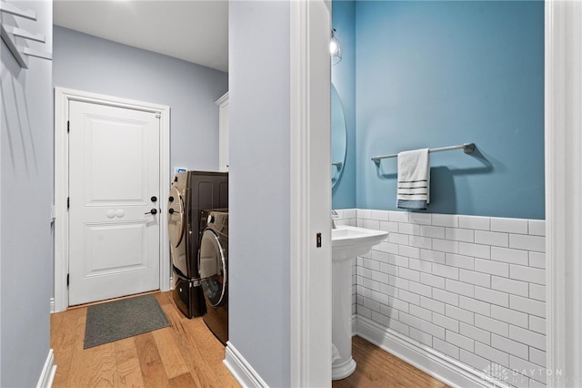 laundry area with light wood-type flooring, tile walls, cabinets, and independent washer and dryer