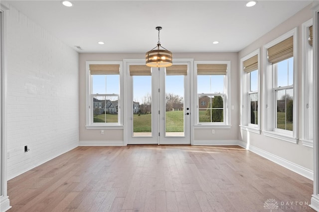 interior space featuring brick wall and light hardwood / wood-style flooring