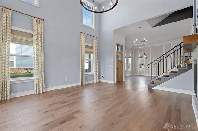 foyer entrance featuring plenty of natural light, a high ceiling, a chandelier, and hardwood / wood-style flooring