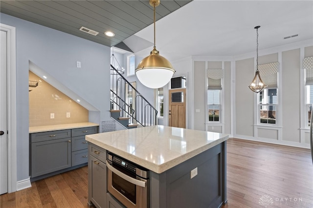 kitchen with decorative light fixtures, a kitchen island, dark hardwood / wood-style flooring, and stainless steel oven