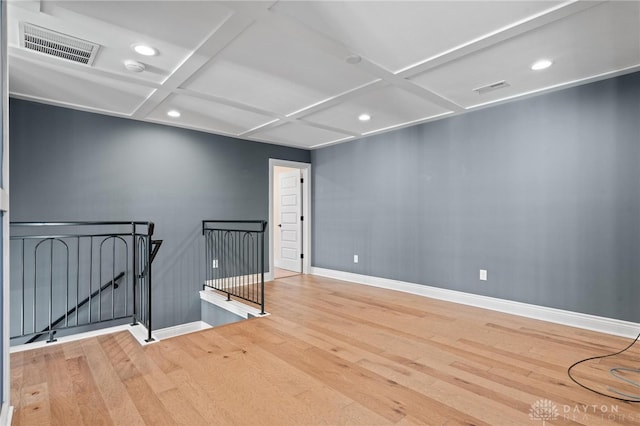 spare room featuring coffered ceiling and hardwood / wood-style flooring