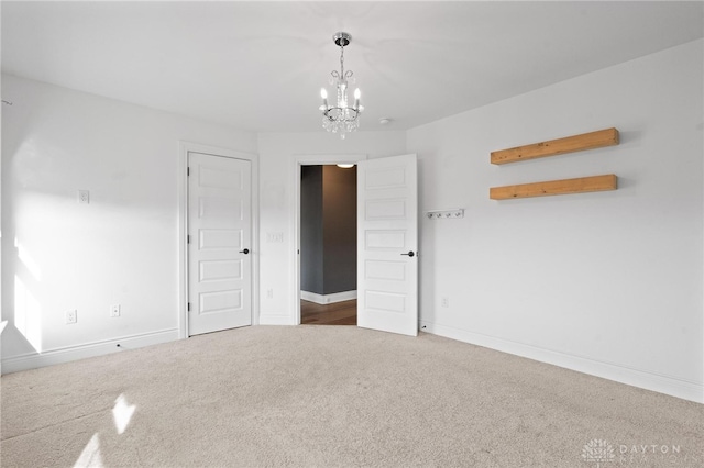 carpeted spare room with a chandelier