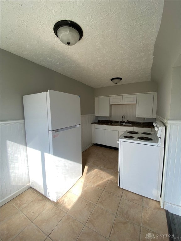 kitchen with white cabinetry, white appliances, a textured ceiling, light tile patterned floors, and sink