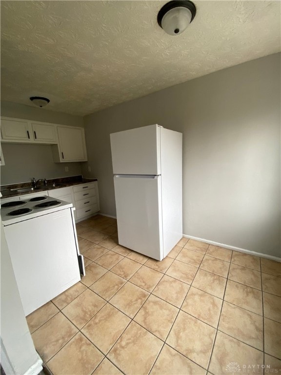 kitchen featuring white cabinets, white appliances, light tile patterned flooring, and a textured ceiling