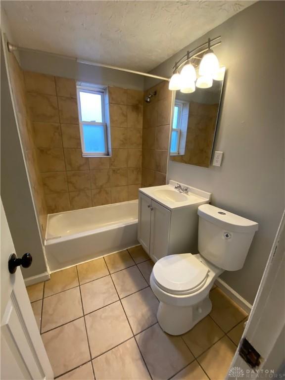 full bathroom with tiled shower / bath combo, vanity, toilet, and tile patterned flooring