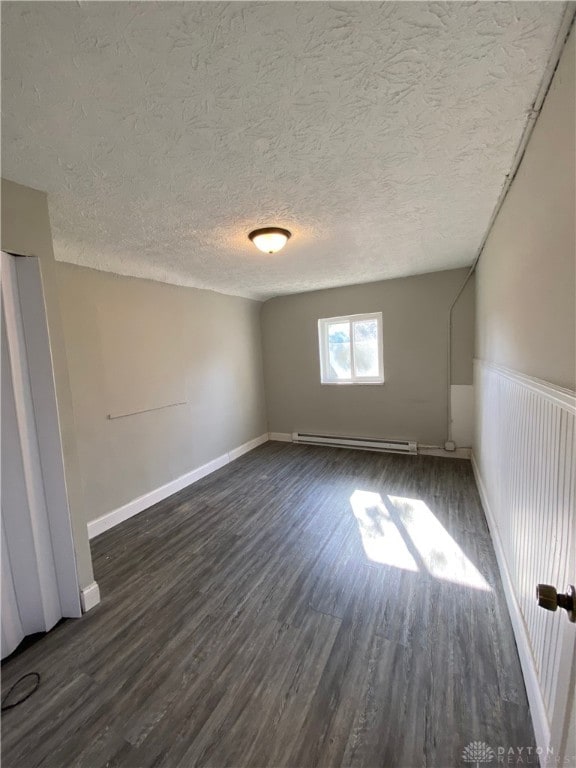 unfurnished room featuring a textured ceiling, a baseboard radiator, and dark hardwood / wood-style floors