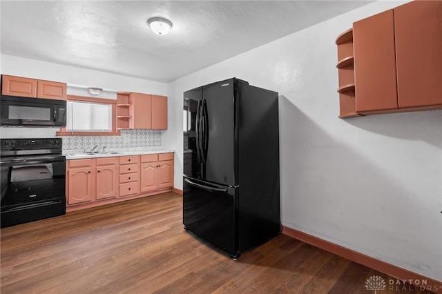 kitchen with black appliances, hardwood / wood-style floors, decorative backsplash, and sink