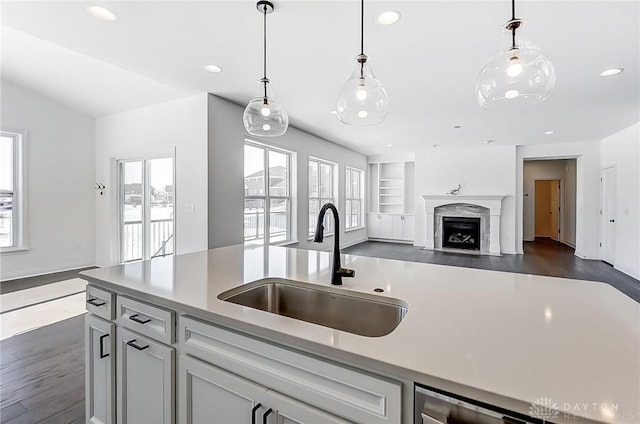 kitchen with pendant lighting, sink, built in shelves, and a wealth of natural light