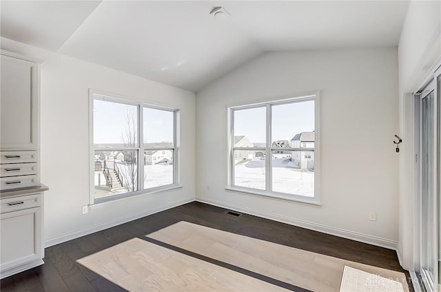 unfurnished dining area with dark wood-type flooring and vaulted ceiling