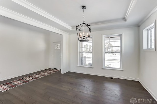 unfurnished dining area featuring dark wood-type flooring, ornamental molding, a raised ceiling, and a chandelier