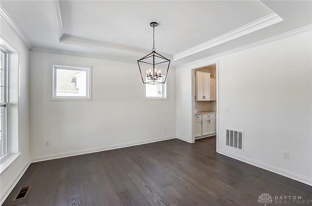 unfurnished dining area with a raised ceiling, crown molding, dark wood-type flooring, and a notable chandelier