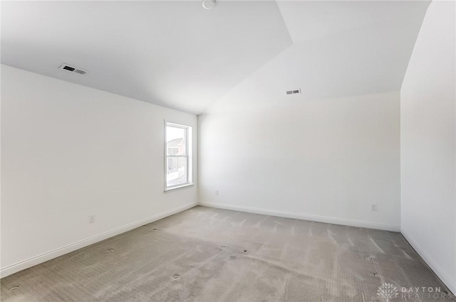 carpeted empty room featuring vaulted ceiling