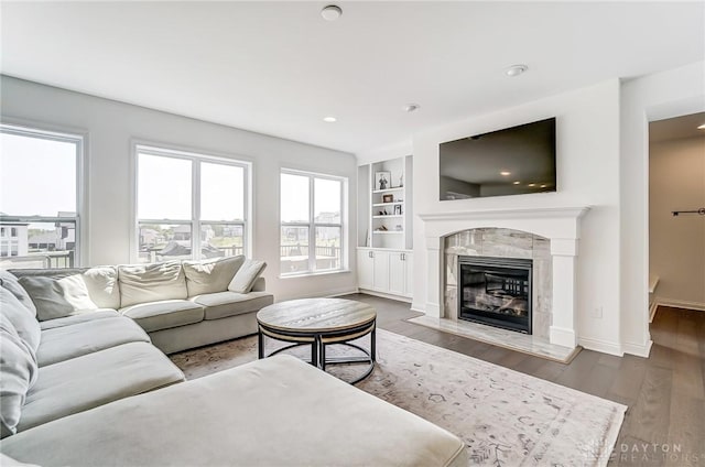 living room featuring built in shelves, a fireplace, hardwood / wood-style flooring, and a wealth of natural light