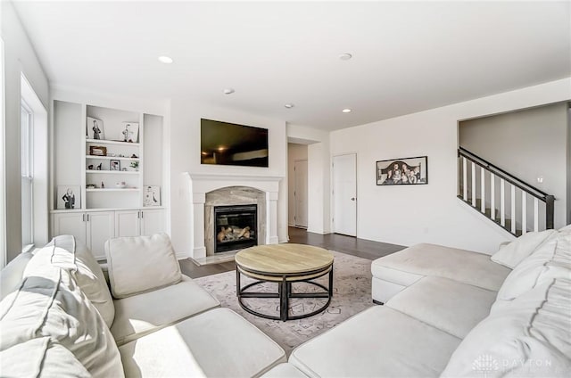 living room with hardwood / wood-style floors, built in features, and a high end fireplace