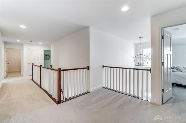 hallway with light carpet and an inviting chandelier