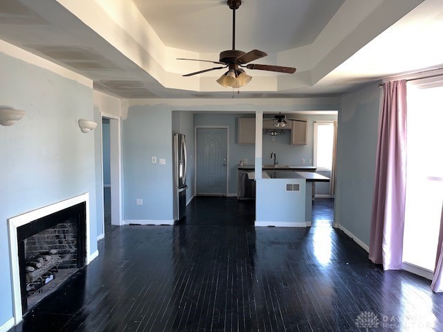 kitchen with a raised ceiling, stainless steel refrigerator, sink, and dark hardwood / wood-style flooring