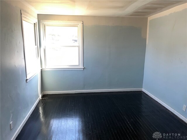 empty room featuring dark wood-type flooring and a healthy amount of sunlight