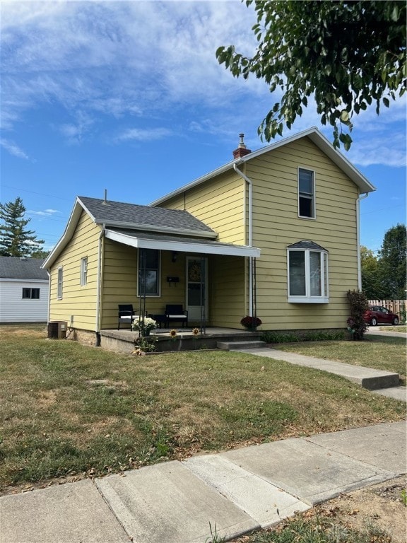 view of front facade with cooling unit, a front lawn, and a porch