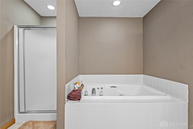 bathroom featuring a textured ceiling and separate shower and tub