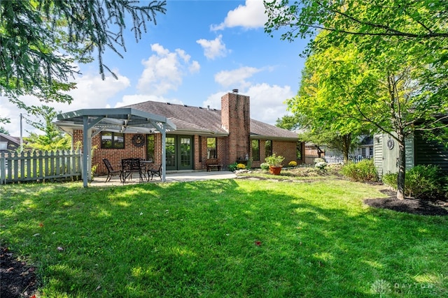 rear view of property featuring a pergola, a patio area, and a lawn