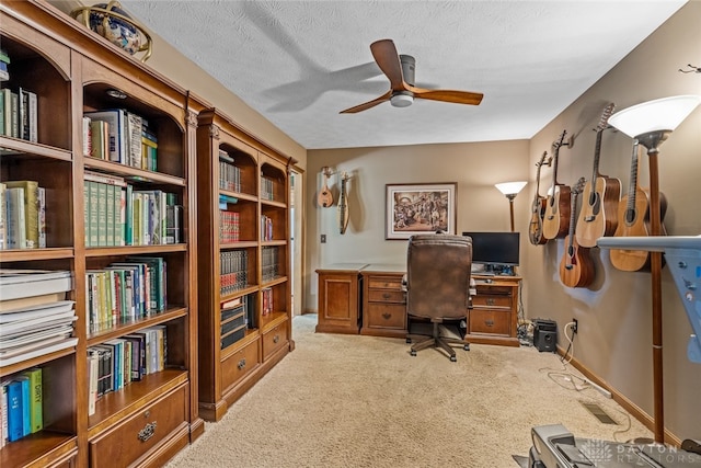 carpeted office space with a textured ceiling and ceiling fan