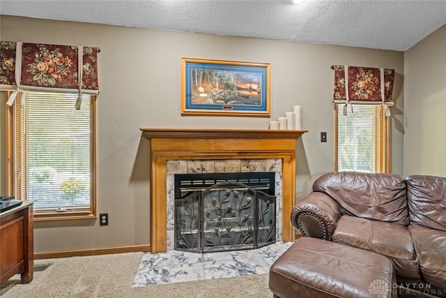 living room with a textured ceiling, carpet flooring, and a tiled fireplace