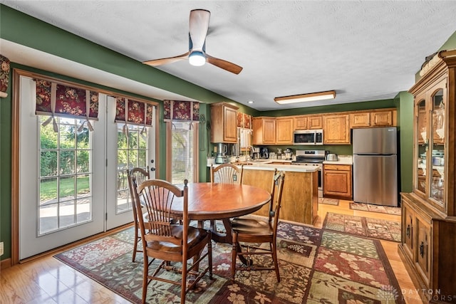 dining room with a textured ceiling, light hardwood / wood-style flooring, and ceiling fan