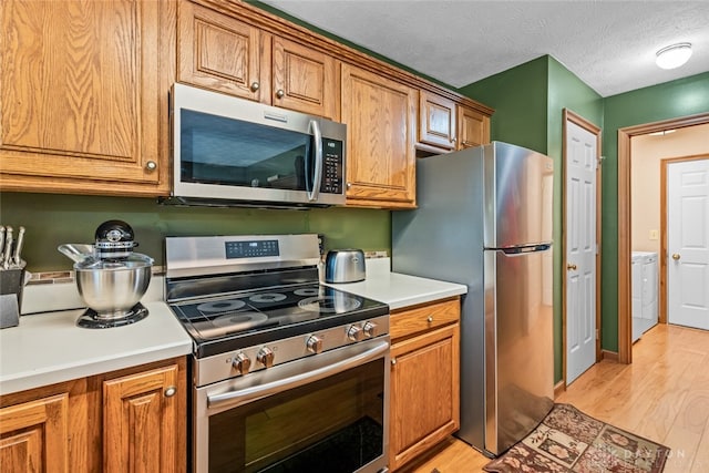 kitchen featuring appliances with stainless steel finishes, a textured ceiling, and light hardwood / wood-style flooring