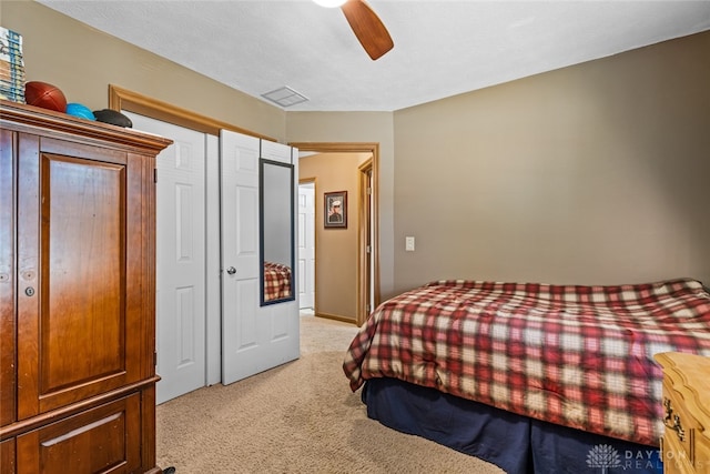 bedroom with a closet, ceiling fan, and light carpet