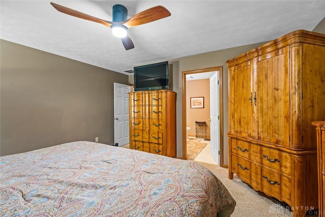 carpeted bedroom with ensuite bath, a textured ceiling, and ceiling fan