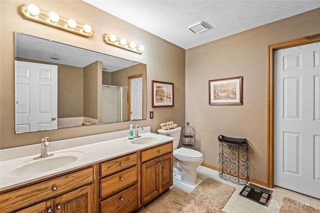 bathroom with a textured ceiling, vanity, toilet, and walk in shower