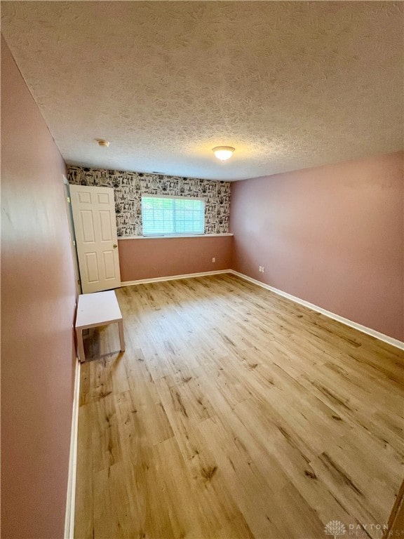 unfurnished room featuring wood-type flooring and a textured ceiling