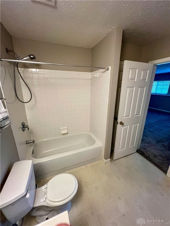 bathroom featuring toilet, tiled shower / bath, and a textured ceiling