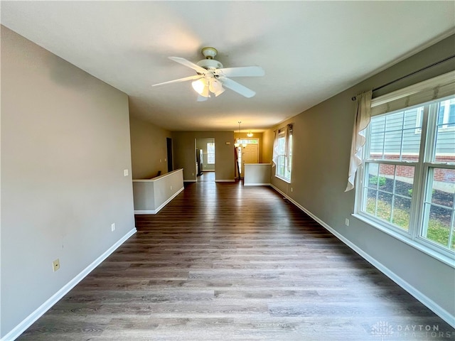 spare room featuring dark hardwood / wood-style floors and ceiling fan with notable chandelier